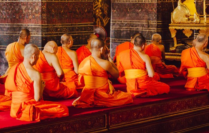 buddhist monks sitting together praying in temple